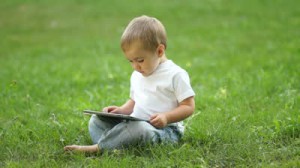 stock-footage-baby-boy-working-with-the-tablet-pc-sitting-on-the-grass